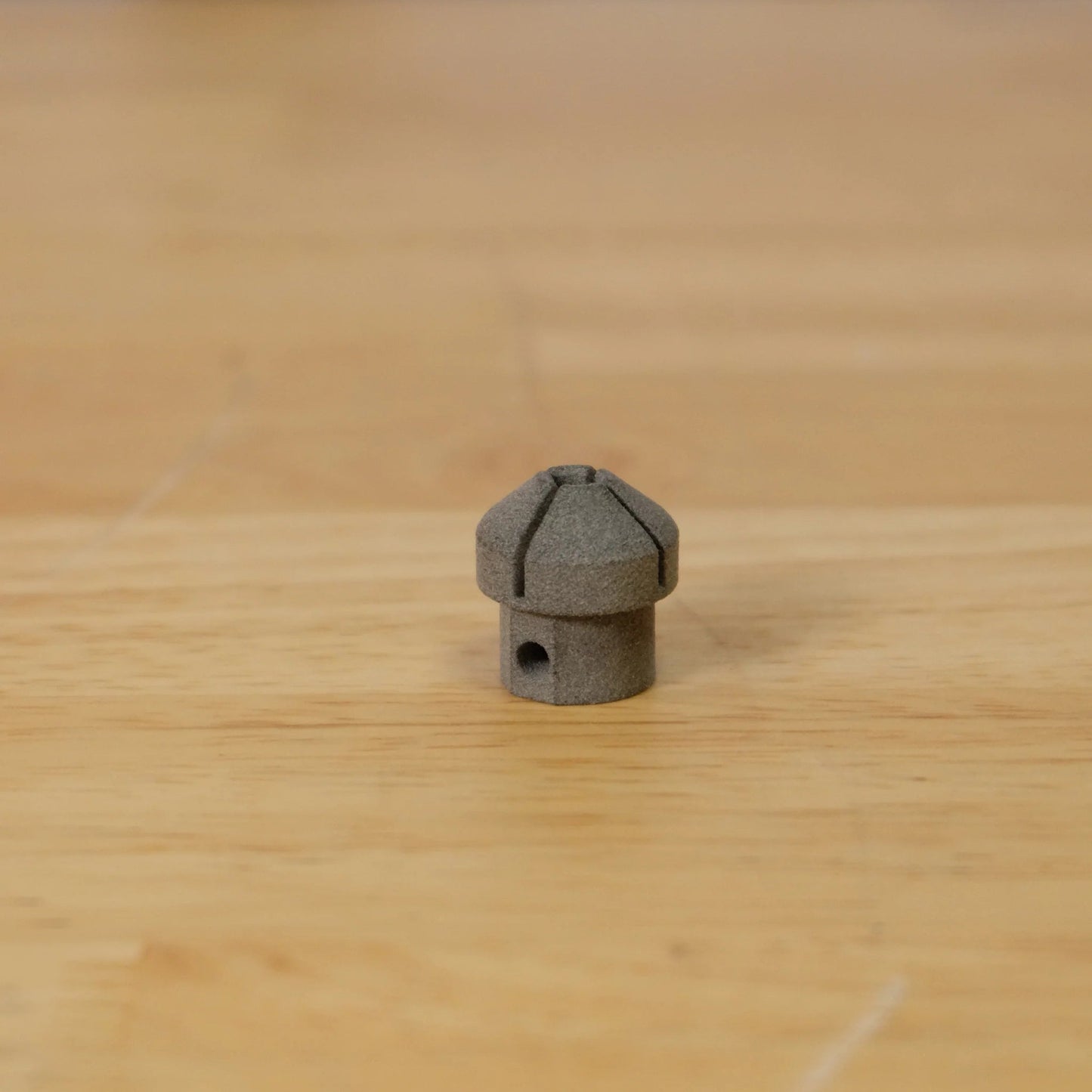 Small grey metal object on a wooden surface